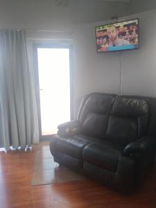 un sofá de cuero negro en la sala de estar con TV de pantalla plana en 16 on Point, en Parow
