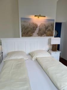 uma cama branca num quarto com uma fotografia na parede em Soling em Laboe