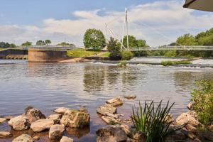 a river with rocks and a bridge in the background at Mill on the Exe in Exeter