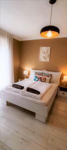 a bedroom with a large white bed with a light at Rigó Apartman in Keszthely