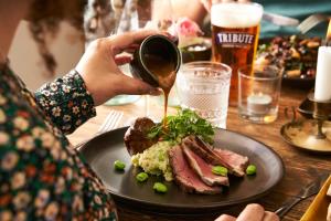 a person is pouring sauce onto a plate of food at Mill on the Exe in Exeter
