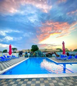 una piscina en un complejo con sillas y una puesta de sol en Hotel Atlantic Costinesti, en Costinesti