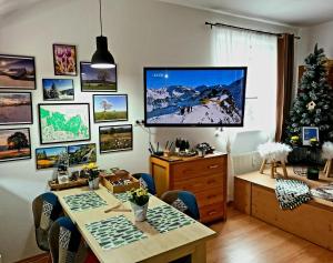 Habitación con mesa y TV en la pared. en Apartmán u Zuzanky, en Svoboda nad Úpou