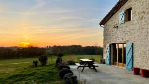 - une table de pique-nique à côté d'un bâtiment avec le coucher du soleil en arrière-plan dans l'établissement Laspeyreres, à Condom