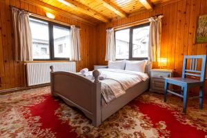 a bedroom with a bed and a chair and two windows at Silva Cabin - In the heart of Bran, next to the Castle w/ free parking in Bran