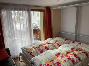 a bedroom with a bed with floral sheets and a window at Aivla in Celerina