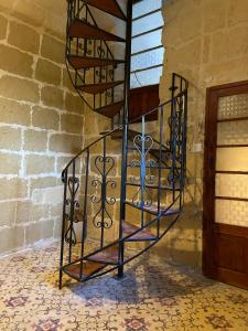 - un escalier en métal en colimaçon dans une pièce dotée d'un mur en briques dans l'établissement Haven Farmhouse With Private Pool, à L-Għarb
