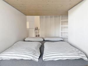 twee bedden in een kleine kamer met gestreepte kussens bij Chesa Auricula in Pontresina