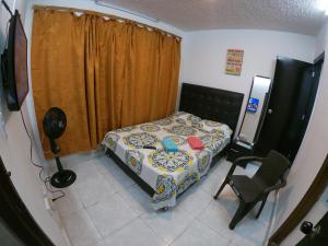 een kleine slaapkamer met een bed en een stoel bij Casa Olimpico Hostal in Cali