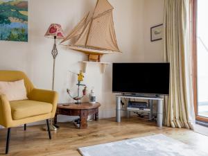a living room with a tv and a chair and a table at 14a Courtenay Street in Salcombe