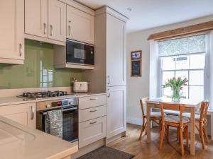 a kitchen with white cabinets and a table with chairs at 14a Courtenay Street in Salcombe