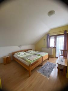 Schlafzimmer mit einem Bett und Holzboden in der Unterkunft Gaál Vendégház in Szentgotthárd