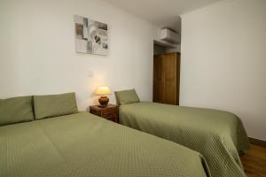 a bedroom with two beds and a lamp on a table at Hospedaria Santa Maria in Beja