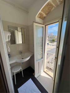 La salle de bains est pourvue d'un lavabo, d'un miroir et d'une fenêtre. dans l'établissement Plaza Rooms, à Avola