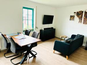 ein Wohnzimmer mit einem Tisch, Stühlen und einem TV in der Unterkunft Das Chorzimmer- Ambiente am Fuße der Burg in Holzhausen
