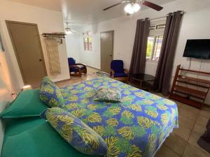1 dormitorio con 1 cama con edredón azul y verde en Fare Tiare en Fare