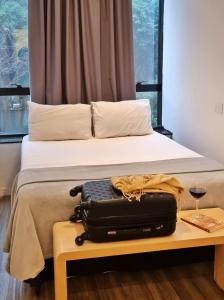 a suitcase sitting on a table next to a bed at Capsula Hotel Sao Paulo - Paulista in Sao Paulo