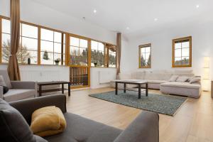 salon z kanapami, stołami i oknami w obiekcie Apartmán Ela w mieście Horní Blatná