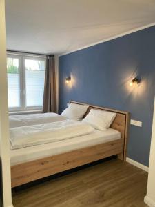 een bed in een slaapkamer met een blauwe muur bij Moderne Ferienwohnung mit Balkon in Herxheim