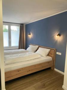 a bed in a bedroom with a blue wall at Moderne Ferienwohnung mit Balkon in Herxheim