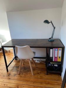 einen Schreibtisch mit einem Stuhl und einer Lampe in der Unterkunft L’appartement du Parc in Longeville-lès-Metz