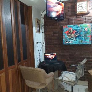 a room with a table with a laptop and a tv on a brick wall at SPACIO HABITACION APART Baño Privado Estar con microondas y frigobar in Mendoza