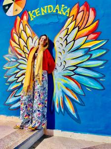 Kobieta stojąca przed ścianą z namalowanym motylem w obiekcie Kendaka Nubian House w mieście Aswan