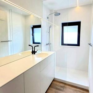 een witte badkamer met een wastafel en een douche bij Cofa'sea designvol appartement in Knokke-Heist