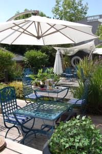 a table and chairs under a white umbrella at Hotel de Charme Le Sud Bretagne in Pornichet