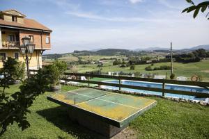 a tennis court sitting in the grass next to a pool at Apartamentos La Gloria in Santillana del Mar