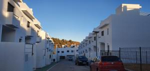 Une rangée de bâtiments blancs avec des voitures garées dans une rue dans l'établissement Home of the Sun - Luminoso adosado con vistas al mar y a 2 km de la playa, à Vélez-Málaga
