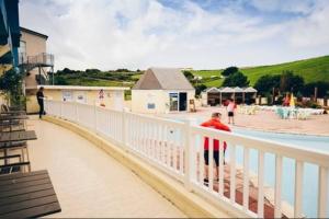 a man standing on a white railing next to a pool at Large 4 person Couples and Family Caravan in Newquay Bay Resort in Newquay