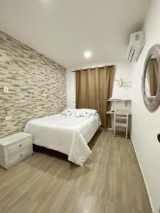 1 dormitorio con cama blanca y pared de ladrillo en Casa Vera Cartagena, en Cartagena de Indias