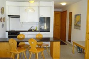 eine Küche mit einem Tisch und gelben Stühlen in einem Zimmer in der Unterkunft Apparthotel Pöstli Nr 305 in Maloja