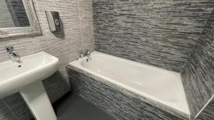 a bathroom with a sink and a bath tub next to a white sink at Hosted By Ryan - 1 Bedroom Apartment in Liverpool