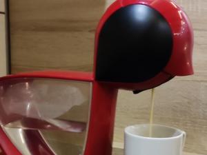 a red coffee maker pouring coffee into a cup at Apartman Sunset Milmari Kopaonik M10 in Kopaonik