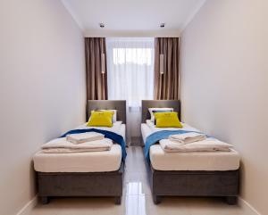 2 camas con almohadas amarillas en una habitación en ApartamentyGdansk eu Mieszkanie Przylesie en Sopot