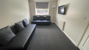 a living room with a black couch and a window at Hosted By Ryan - 2 Bedroom Apartment in Liverpool