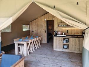 a kitchen with a table and chairs in a tent at Moulin Du Pommier Glamping & Camping in Saulgond