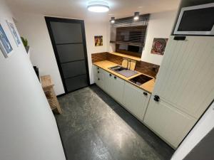 una pequeña cocina con armarios blancos y fregadero en Cichy Apartament Gdańsk, en Gdansk