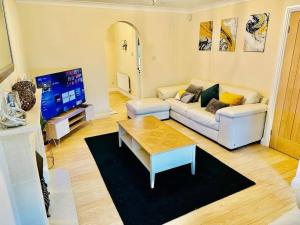 uma sala de estar com um sofá branco e uma televisão em Spacious & modern 3 bedroom house in Peterlee em Wingate