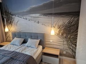 a bedroom with a bed and a picture of a beach at Apartament Baltic Park - BEL MARE 2 in Pogorzelica