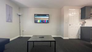 a living room with a table and a tv on the wall at Hosted By Ryan - 2 Bedroom Apartment in Liverpool