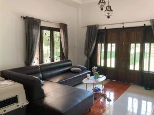 - un salon avec un canapé en cuir noir et des fenêtres dans l'établissement Mysigt hus i Sichon, à Sichon