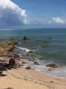 2 personnes assises sur la plage près de l'océan dans l'établissement Mysigt hus i Sichon, à Sichon