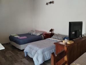 1 Schlafzimmer mit 2 Betten, einem TV und einem Schreibtisch in der Unterkunft LuMar3 in Comodoro Rivadavia
