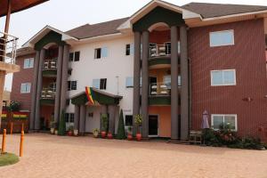 a large brick building with a flag in front of it at Golden Crystal Experience Hotel in Accra