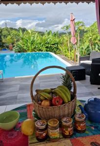 a basket of fruit on a table in front of a pool at Maison Jean in Le Gosier
