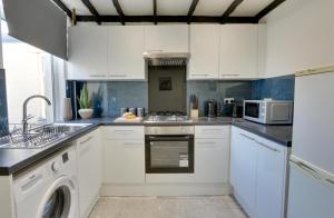 cocina con armarios blancos, lavadora y secadora en Cozy 2-bedroom house in Sheffield en Tankersley