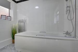 Baño blanco con bañera y lavamanos en Cozy 2-bedroom house in Sheffield en Tankersley